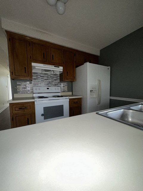 an empty kitchen with white appliances and wooden cabinets