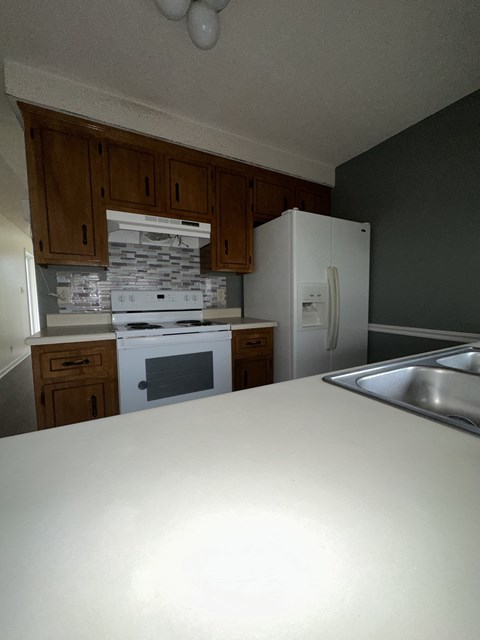 A kitchen with a white counter top and wooden cabinets.