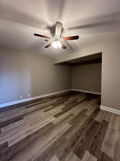 a living room with wood flooring and a ceiling fan