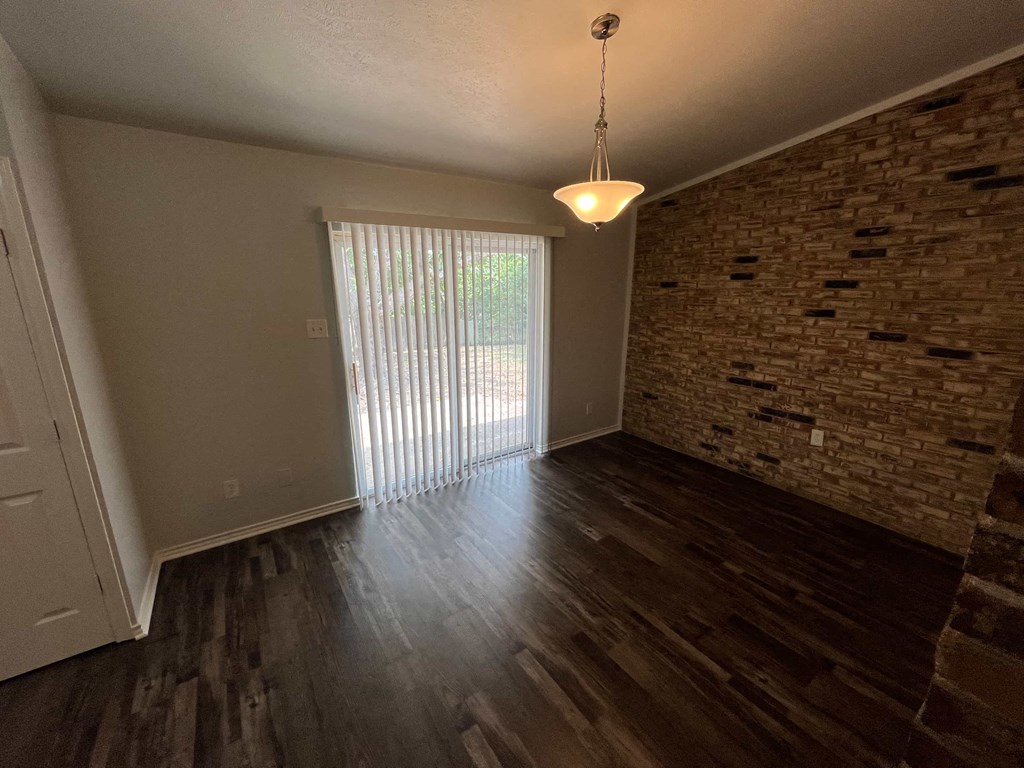 an empty living room with a brick wall and a sliding glass door