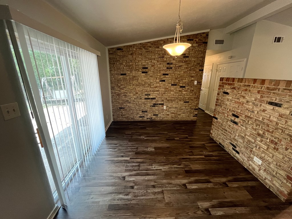 a hallway with a brick wall and a sliding glass door