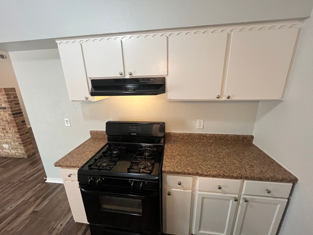 a kitchen with white cabinets and a stove and a counter top