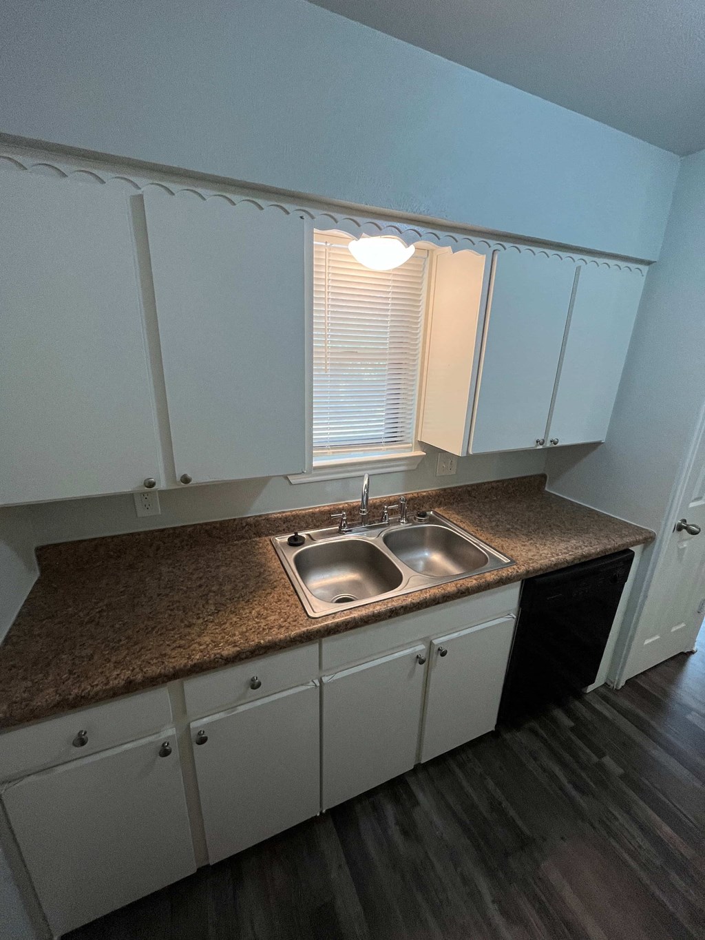 an empty kitchen with white cabinets and a counter top and a sink