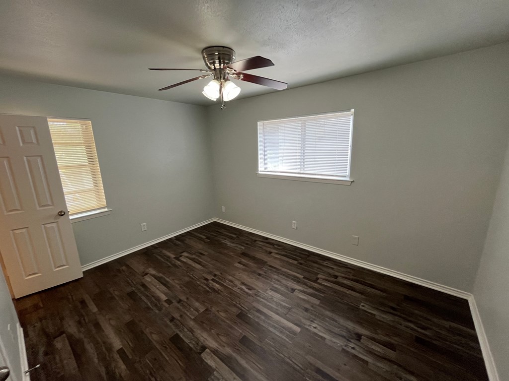 a bedroom with a ceiling fan and wood floors