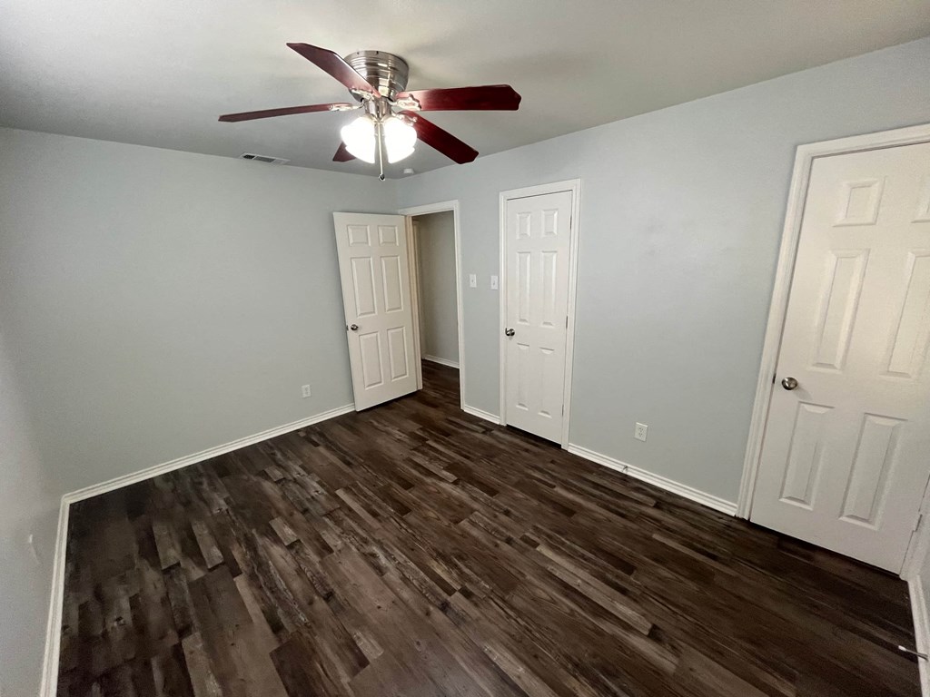 an empty living room with wood flooring and a ceiling fan