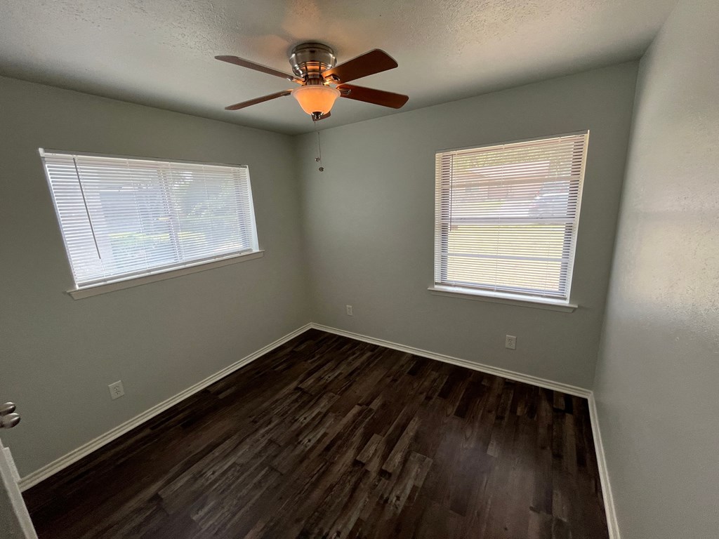 the bedroom has hardwood floors and a ceiling fan