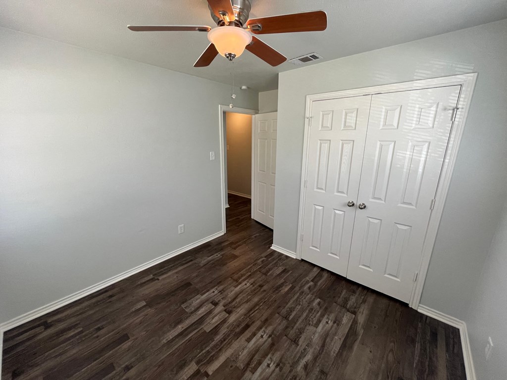 a bedroom with a ceiling fan and a closet