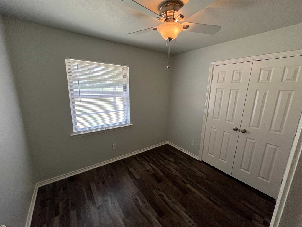 a bedroom with a ceiling fan and wood floors