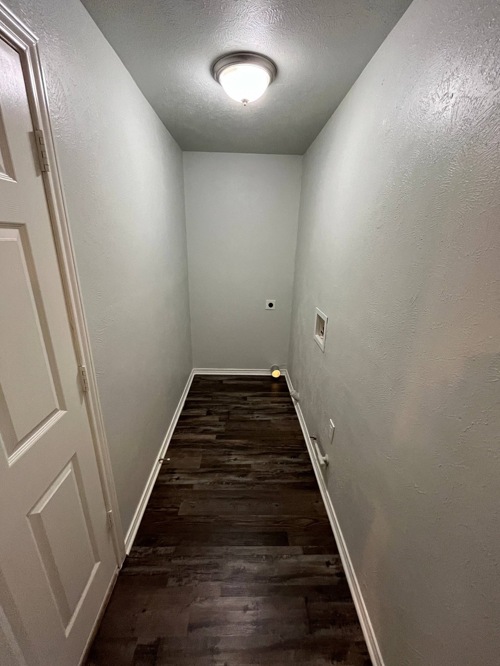 a long hallway with wood flooring and a white door