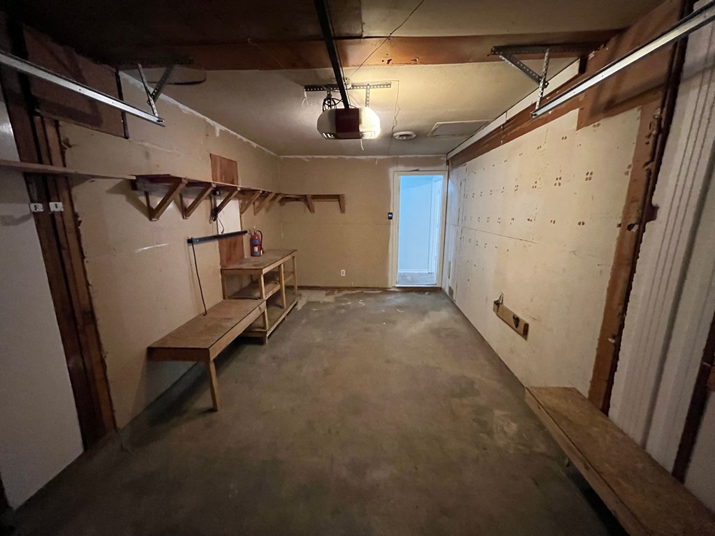 a room in a unfinished basement with a bench and a window