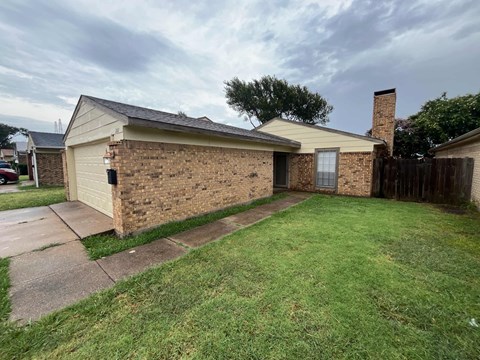 a brick house with a yard and a sidewalk