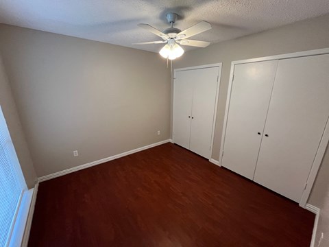a bedroom with wood floors and a ceiling fan