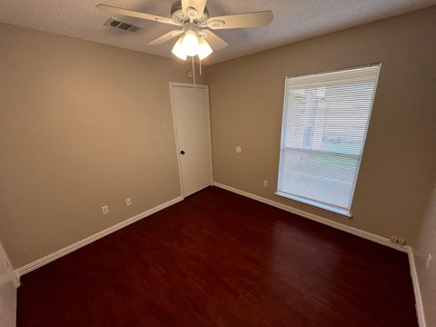 a living room with wood floors and a ceiling fan