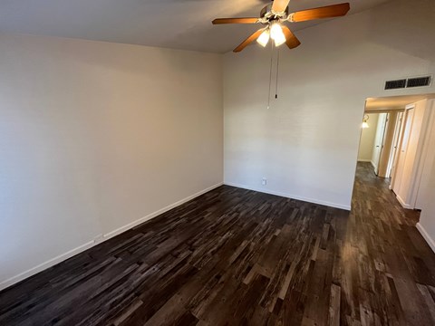 A room with a ceiling fan and wooden flooring.