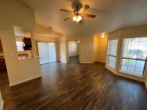 A room with a ceiling fan and wooden flooring.