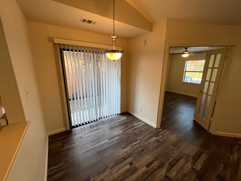 A room with wooden floors and a window with blinds.
