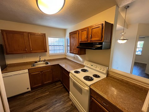 A kitchen with a white stove top oven and wooden cabinets.