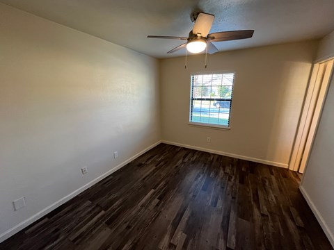 A room with a ceiling fan and a window showing a view of a pool.