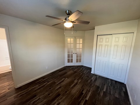A room with a ceiling fan and wooden flooring.