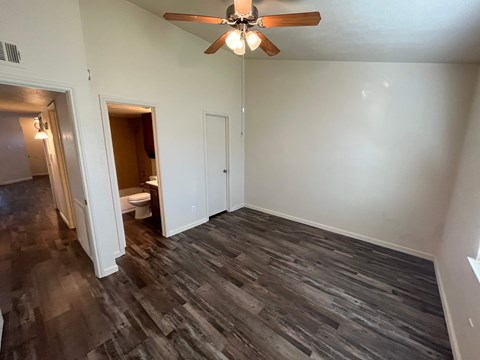 A room with a ceiling fan and wood flooring.