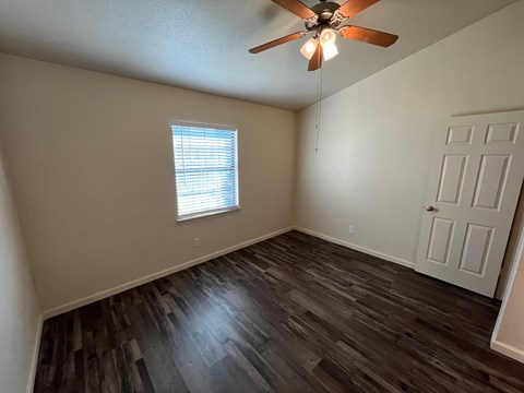 A room with a ceiling fan and a window with blinds.
