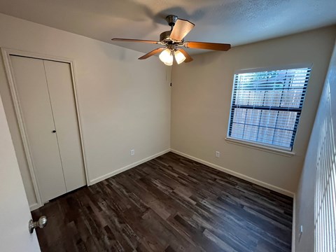 A room with a ceiling fan and a window with blinds.