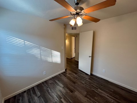 A room with a ceiling fan and wooden flooring.