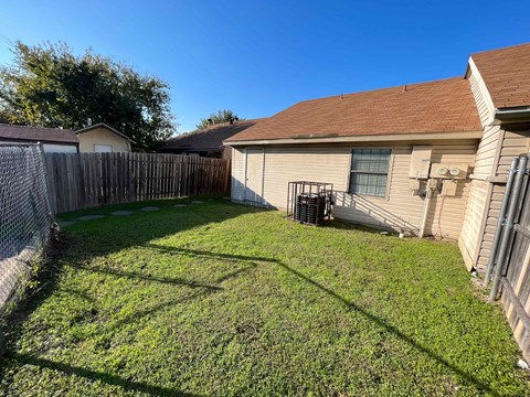 A backyard with a fence and a house in the background.