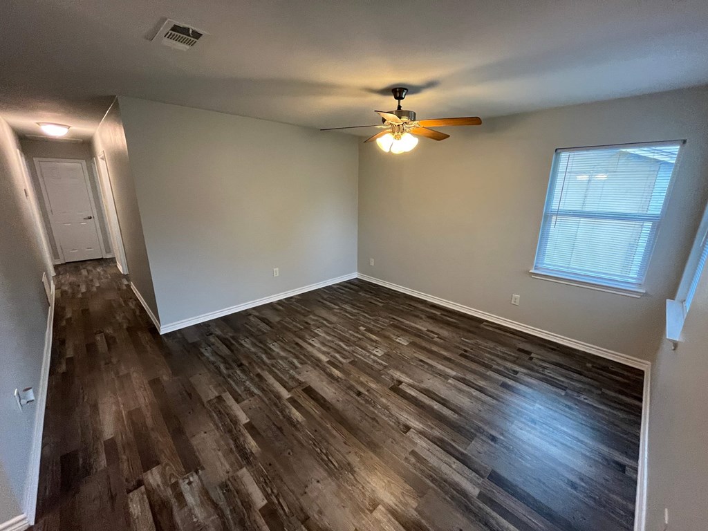 A room with wooden flooring and a ceiling fan.