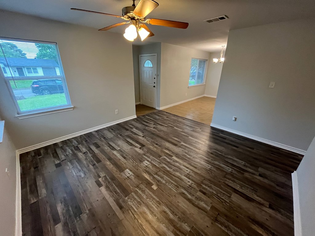 A room with a ceiling fan and wooden flooring.