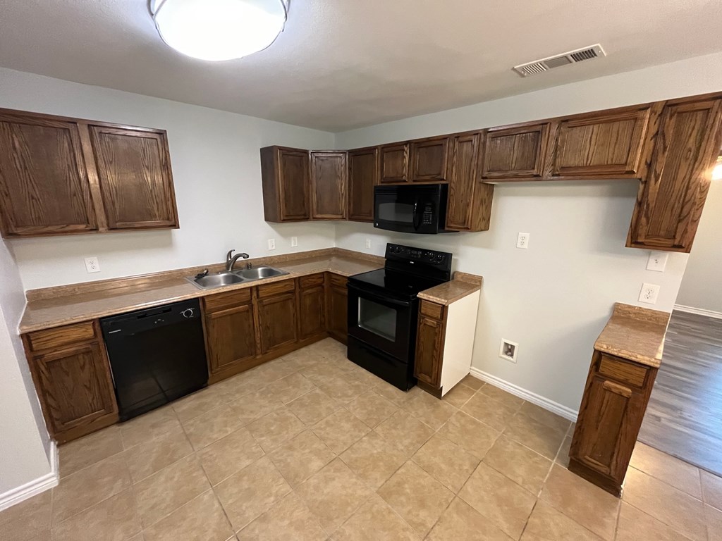 A kitchen with black appliances and wooden cabinets.