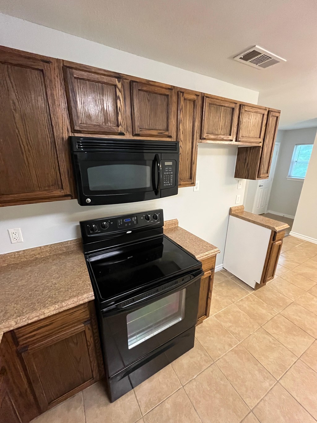 A kitchen with brown cabinets and black appliances.
