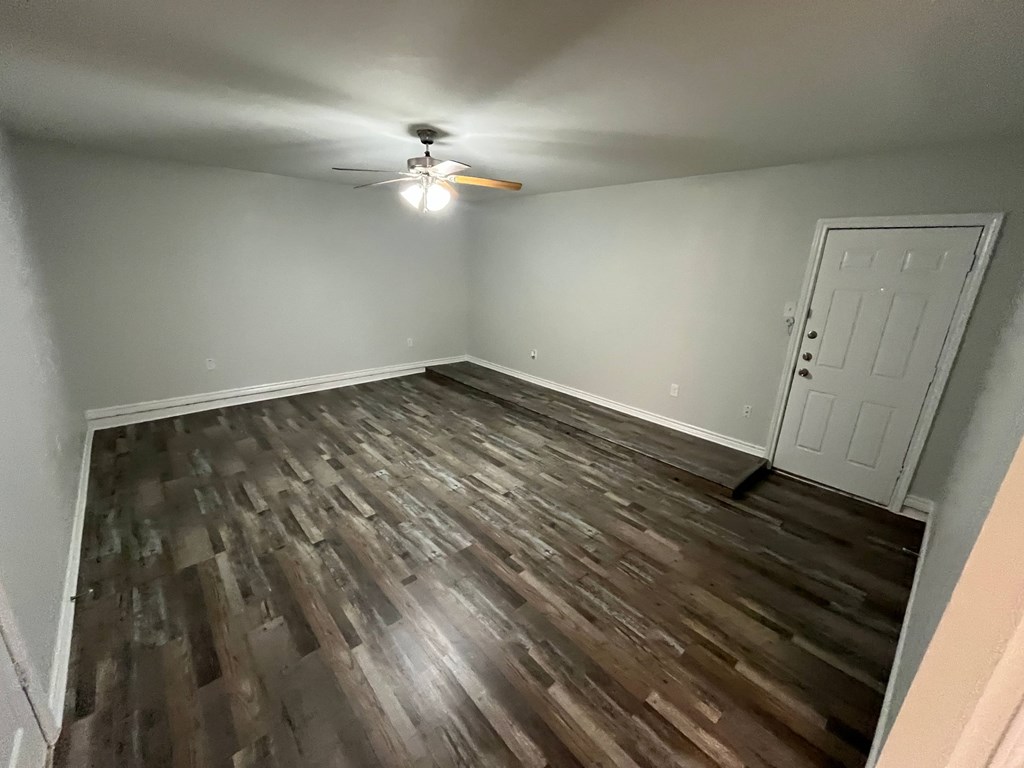 A room with wooden flooring and a ceiling fan.