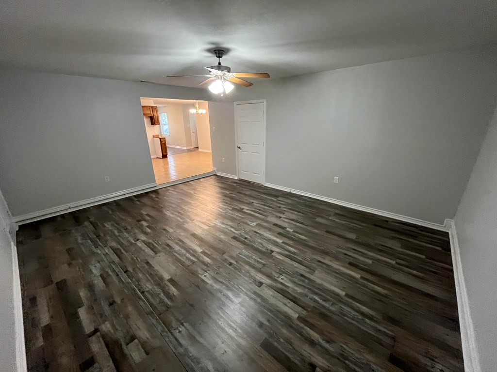 A room with a ceiling fan and wood flooring.