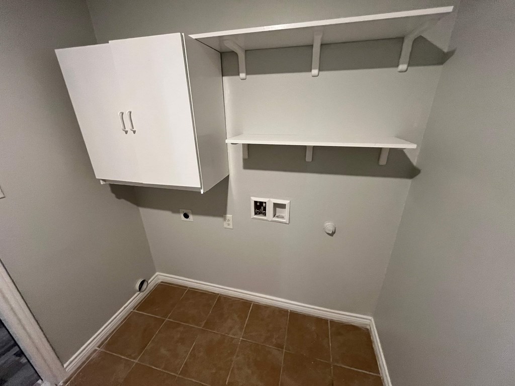 A white cabinet with two doors and two shelves is mounted on a wall.