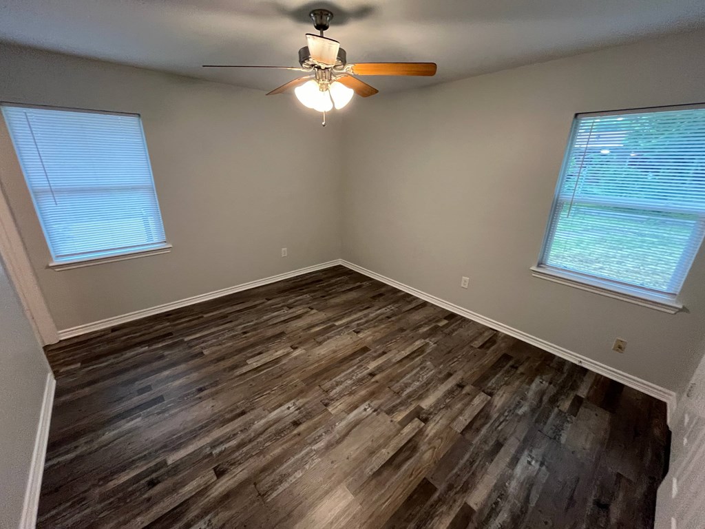 A room with a ceiling fan and wooden flooring.