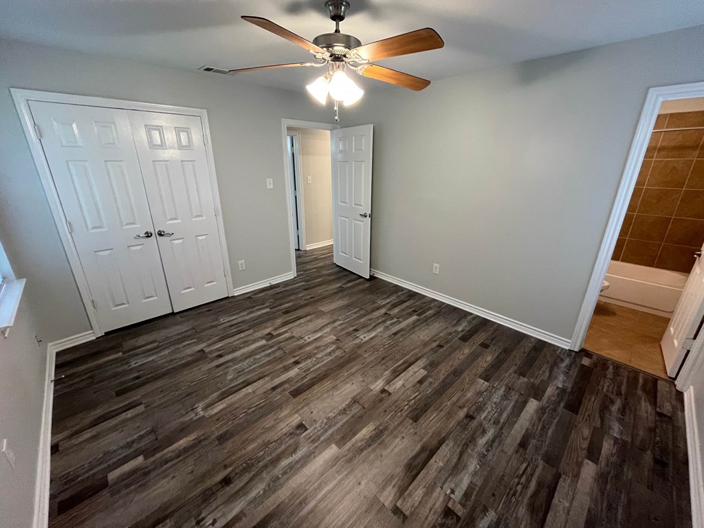 A room with a ceiling fan and wooden flooring.