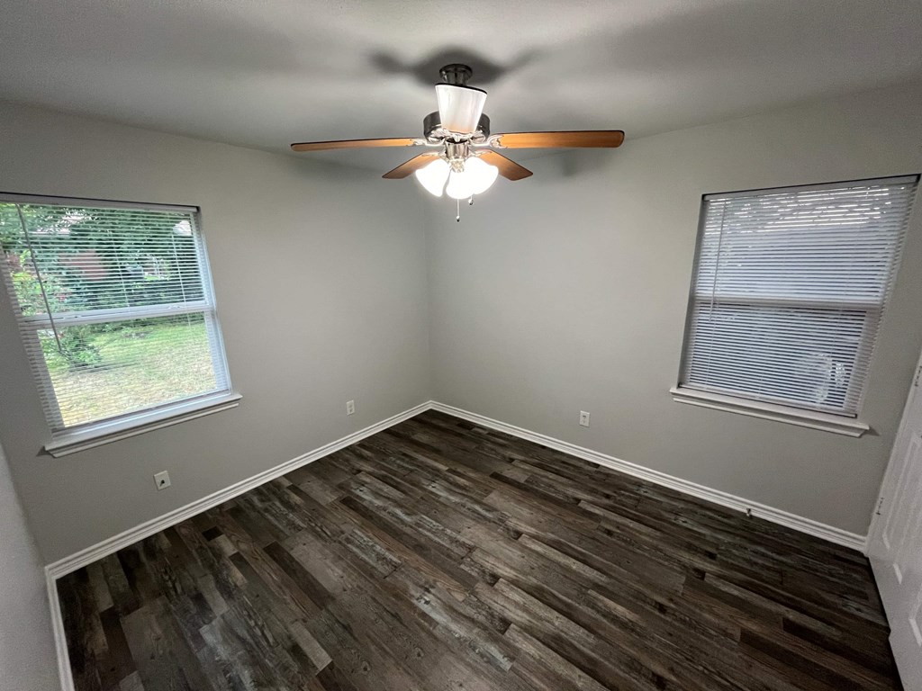 A room with a ceiling fan and wooden flooring.