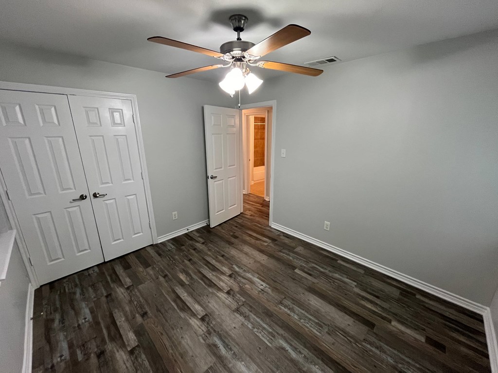A room with a ceiling fan and wooden flooring.