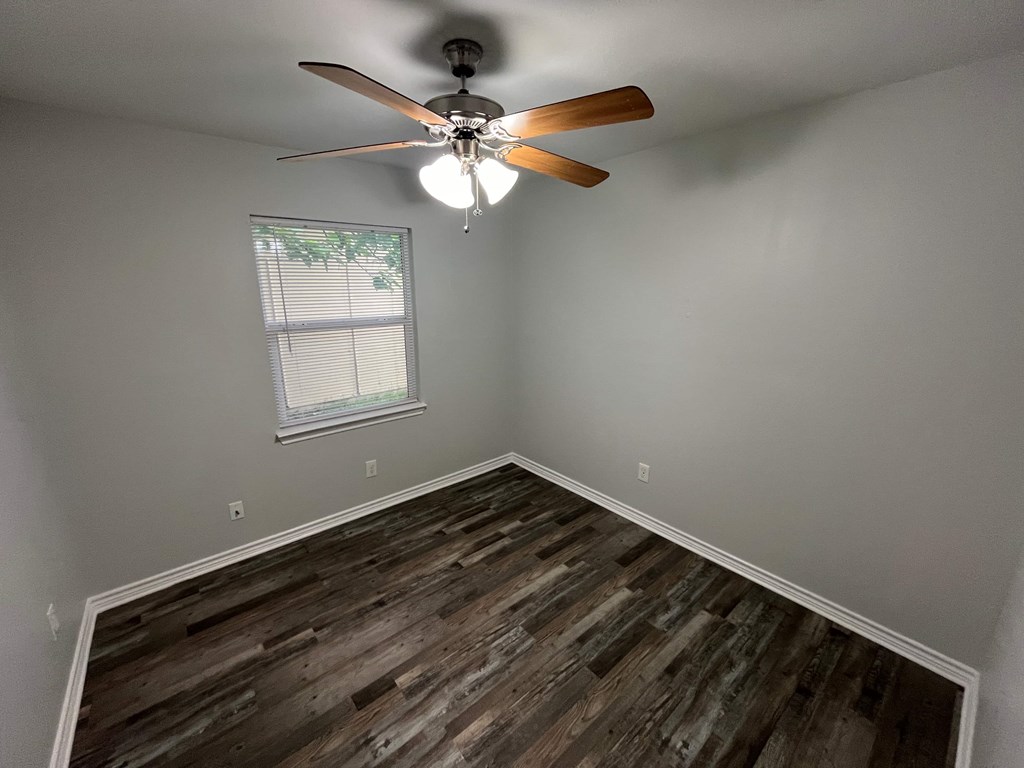 A room with a ceiling fan and wooden flooring.
