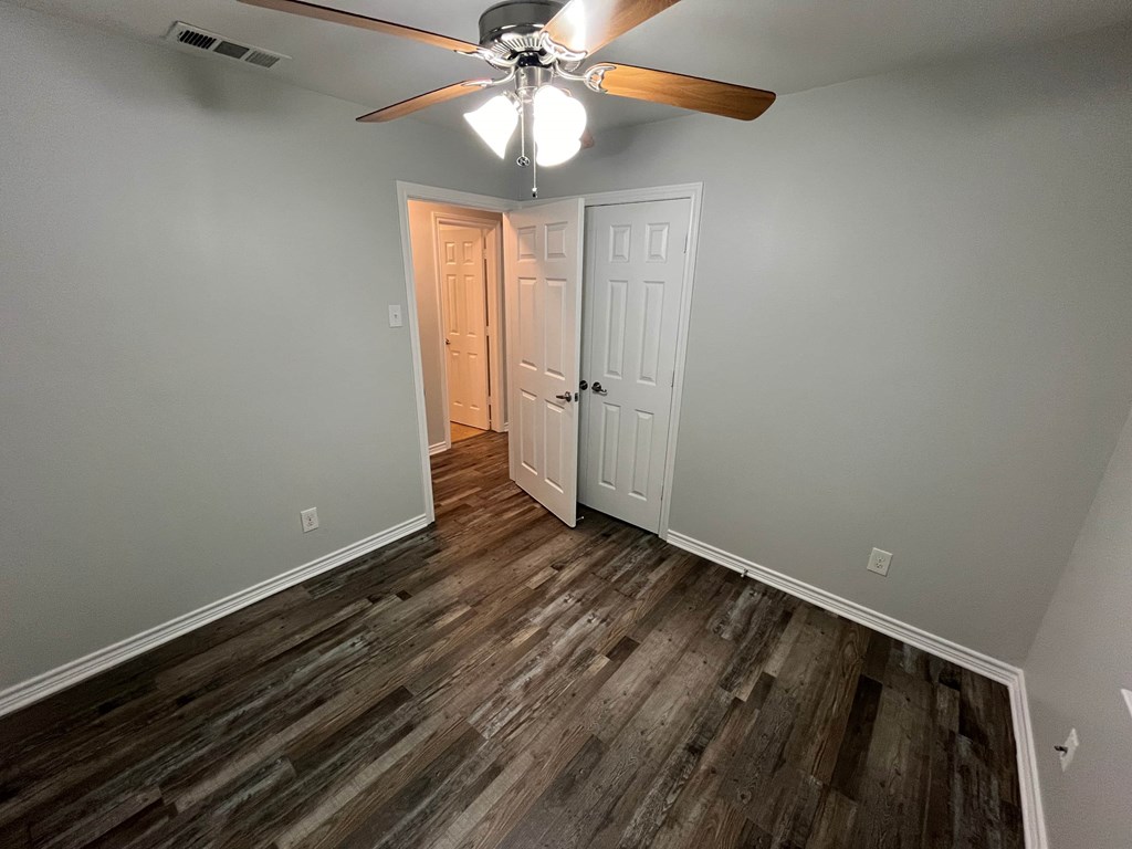 A room with a ceiling fan and wooden flooring.
