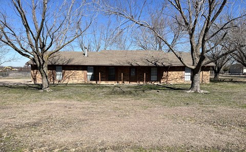 a brown brick house with trees in front of it