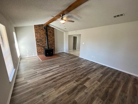 an empty living room with wood flooring and a ceiling fan