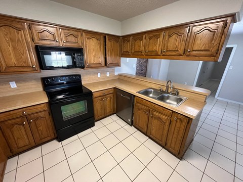 a kitchen with wooden cabinets and a black stove and a sink