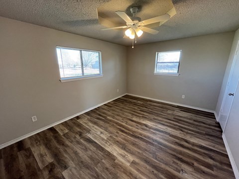 an empty living room with wooden floors and a ceiling fan