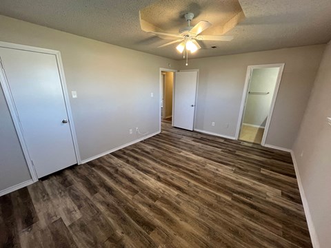 an empty living room with wood flooring and a ceiling fan