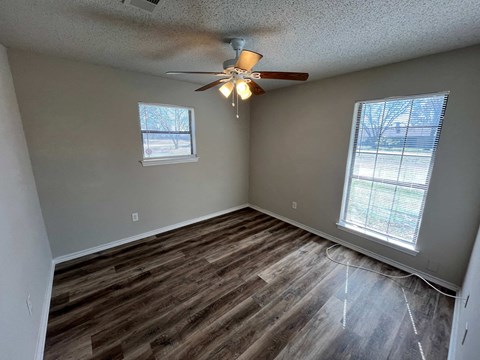an empty living room with wood floors and a ceiling fan