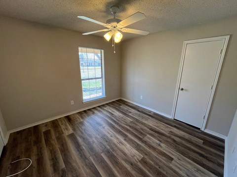 an empty living room with wooden floors and a ceiling fan