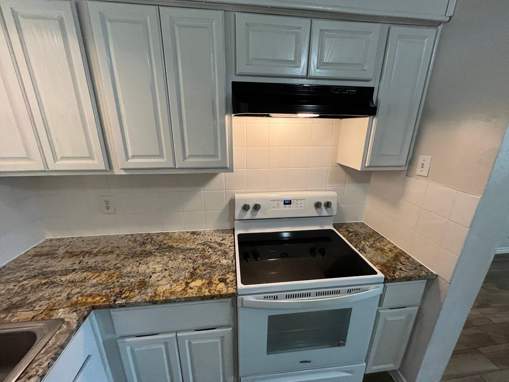 a kitchen with white cabinets and a stove and a counter top