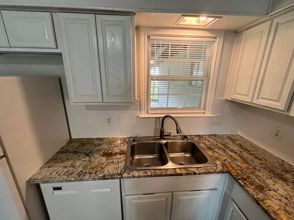 a kitchen with white cabinets and granite counter tops and a sink